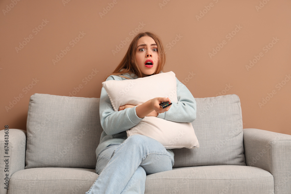 Scared young woman with TV remote control watching movie in living room Scared young woman with TV remote control watching movie in living room
