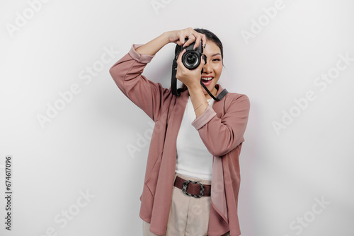 Happy smiling young Asian woman tourist standing with camera taking photo isolated on white studio background
