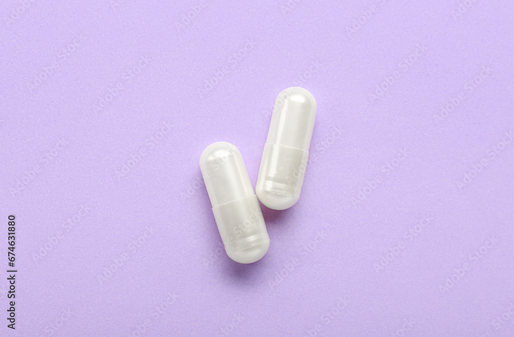 White capsules on purple background White capsules on purple background