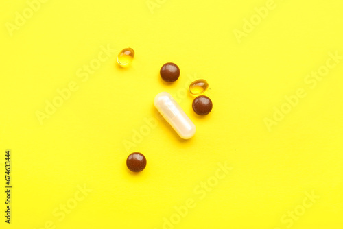 Different medical pills on yellow background