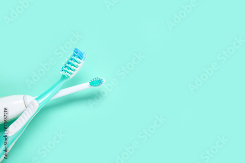 Electric and plastic toothbrushes on color background.