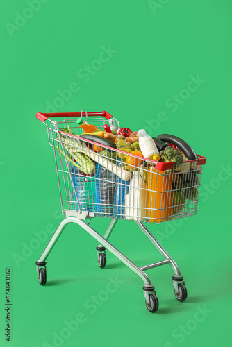 Shopping cart full of food on green background