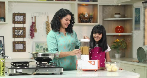 Happy Mother And Daughter Preparing Fruit Juice At Table In Kitchen
