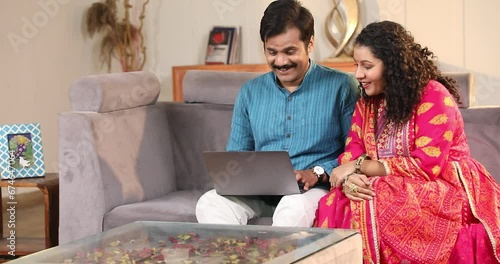 Happy Married Couple Spend Time Sitting On Sofa At Home Shopping Online on laptop
