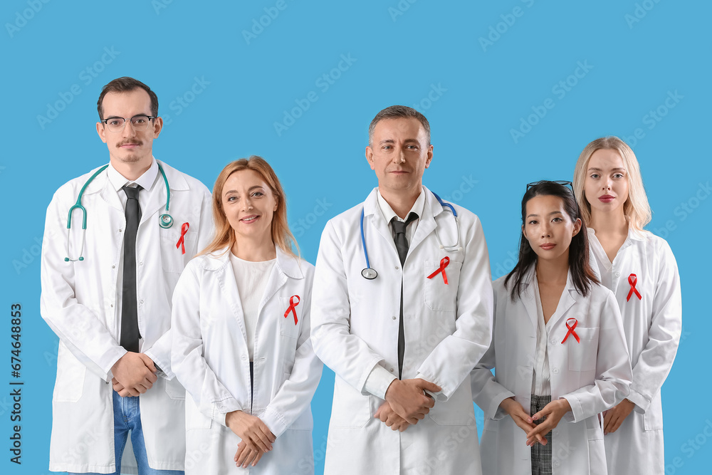 Professional team of doctors with red ribbons on blue background. World AIDS Day concept Professional team of doctors with red ribbons on blue background. World AIDS Day concept