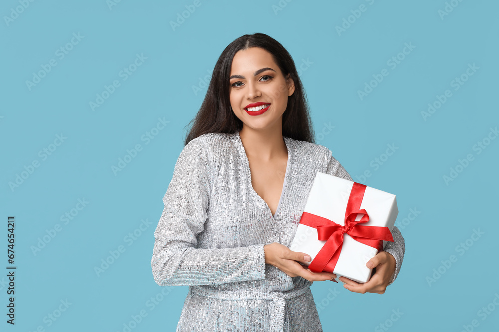 Beautiful young woman with Christmas gift on blue background Beautiful young woman with Christmas gift on blue background