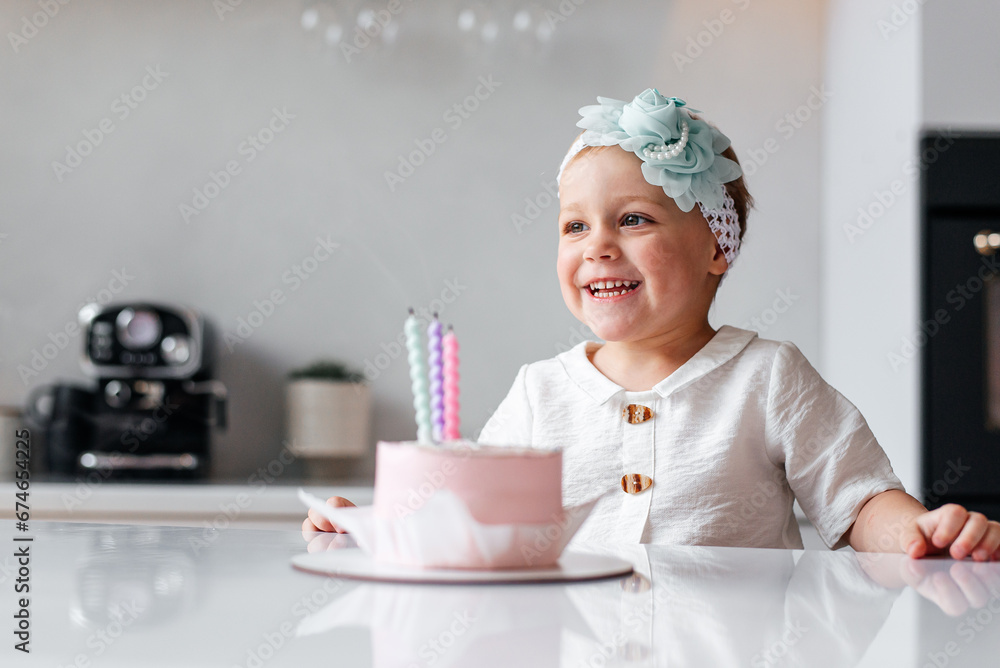 Adorable birthday girl making wish blowing candles on the cake. 3 years old toddler kid celebrating and enjoying Adorable birthday girl making wish blowing candles on the cake. 3 years old toddler kid celebrating and enjoying
