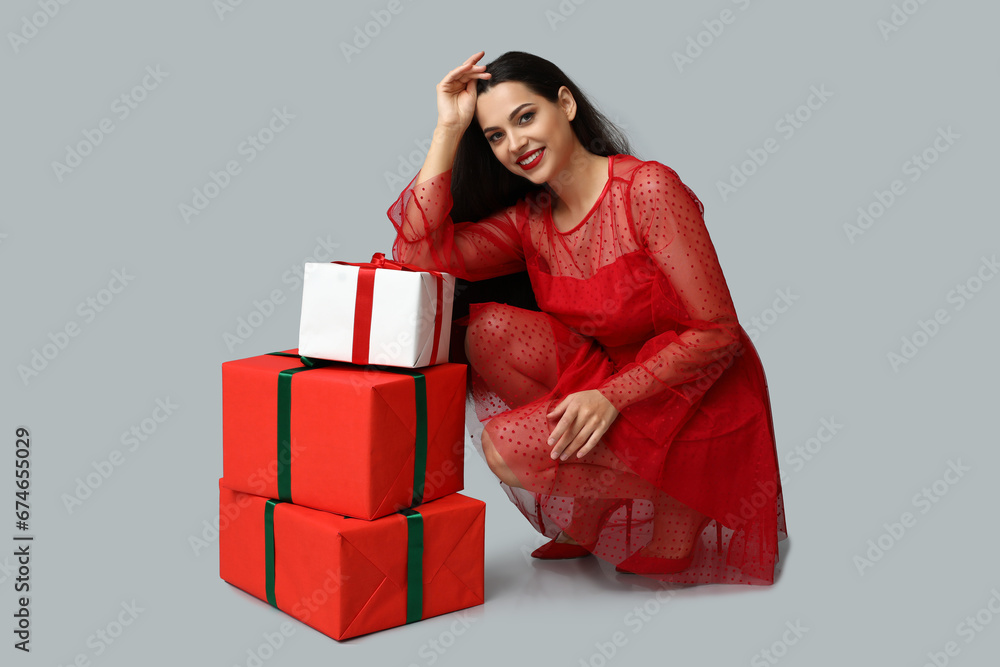 Beautiful young woman with Christmas gifts on grey background Beautiful young woman with Christmas gifts on grey background