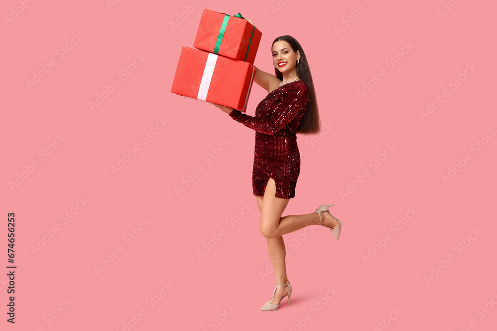 Beautiful young woman with Christmas gifts on pink background Beautiful young woman with Christmas gifts on pink background