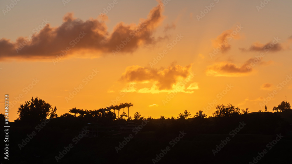 Panorama of orange  sunset view of ridge in silhouette near Kilauea, Kauai, Hawaii, United States.
