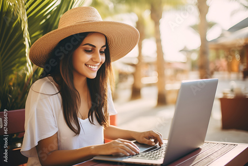 Freelancer woman in a hat with a laptop among tropical palm trees
