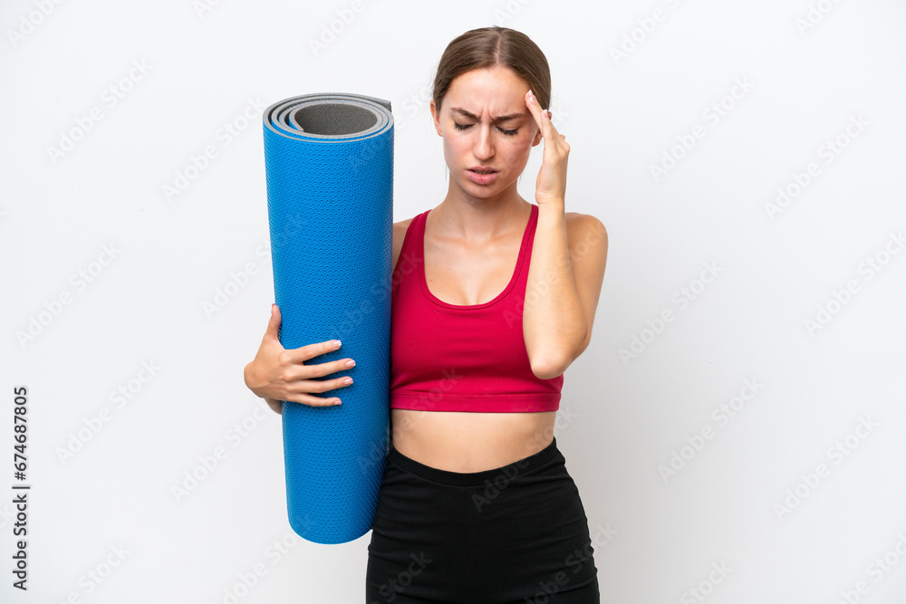Young sport caucasian woman going to yoga classes while holding a mat isolated on white background with headache