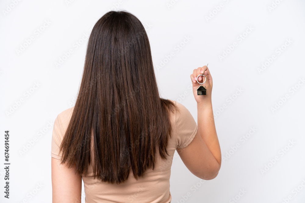 Young Brazilian woman holding home keys isolated on white background in back position Young Brazilian woman holding home keys isolated on white background in back position
