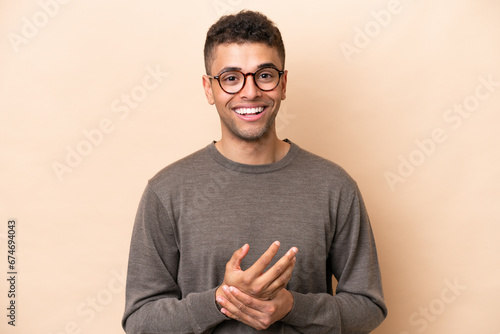 Young Brazilian man isolated on beige background laughing