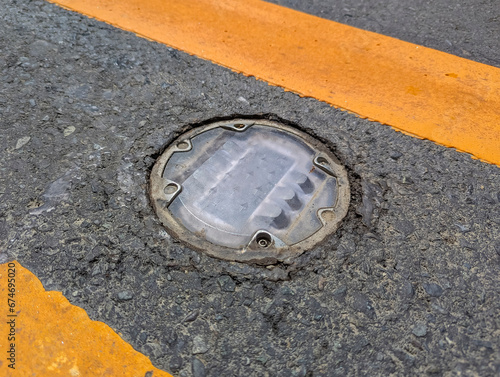 Daytime view of recessed solar road stud markers embedded in the center lane of an asphalted highway. Also known as a road reflector. photo