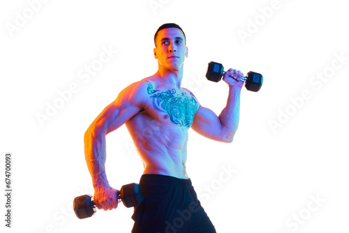 Shirtless young man with strong, muscular fit body training with dumbbells against white studio background in neon light. Concept of sport, active and healthy lifestyle, body care, fitness