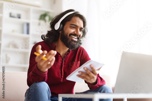 Indian guy attending webinar or online course, home interior photo