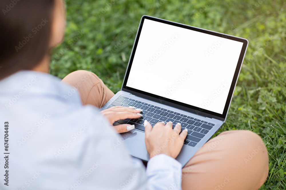 Young caucasian woman enjoy work, typing on laptop with empty screen, sit on grass Young caucasian woman enjoy work, typing on laptop with empty screen, sit on grass