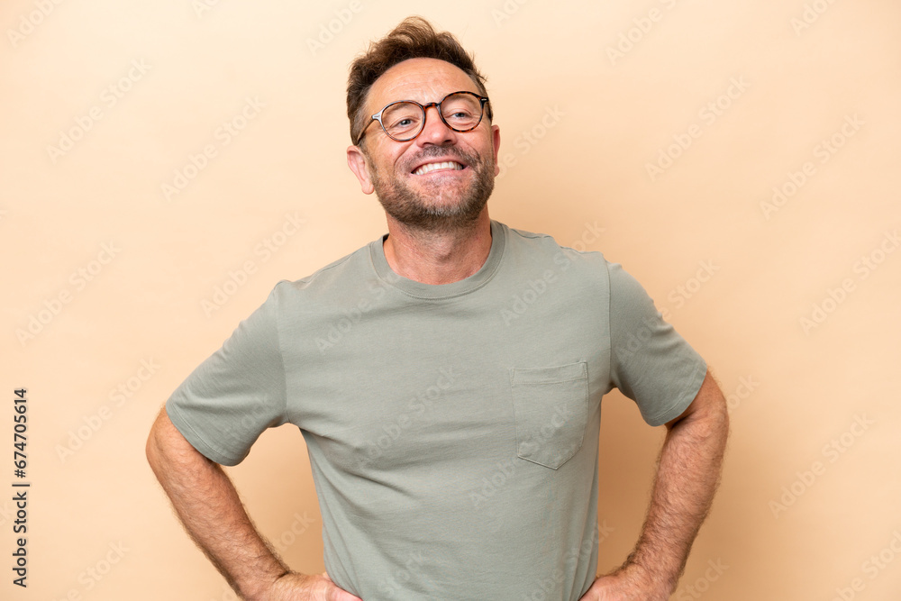 Middle age caucasian man isolated on beige background posing with arms at hip and smiling Middle age caucasian man isolated on beige background posing with arms at hip and smiling