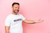 Middle age volunteer man isolated on pink background isolated on pink background extending hands to the side for inviting to come
