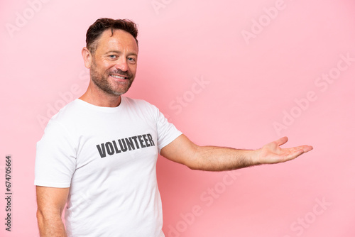 Middle age volunteer man isolated on pink background isolated on pink background extending hands to the side for inviting to come photo