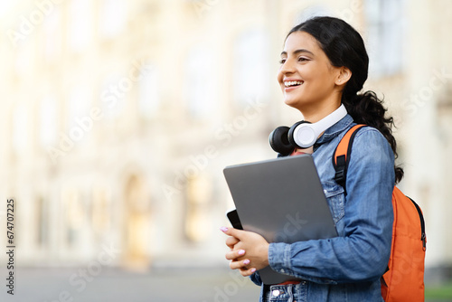 Excited pretty young indian woman student with backpack and laptop © Prostock-studio