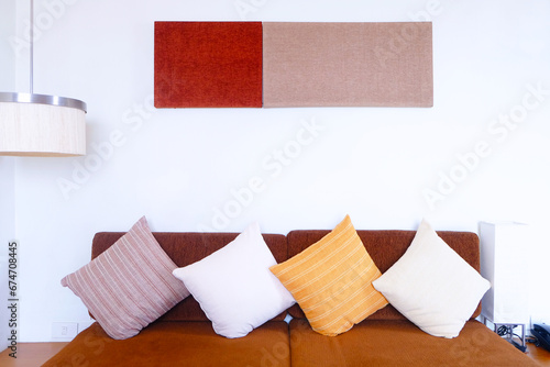 Front face empty red sofa with pillows arranged on it, white wallpaper and lamps and decorations