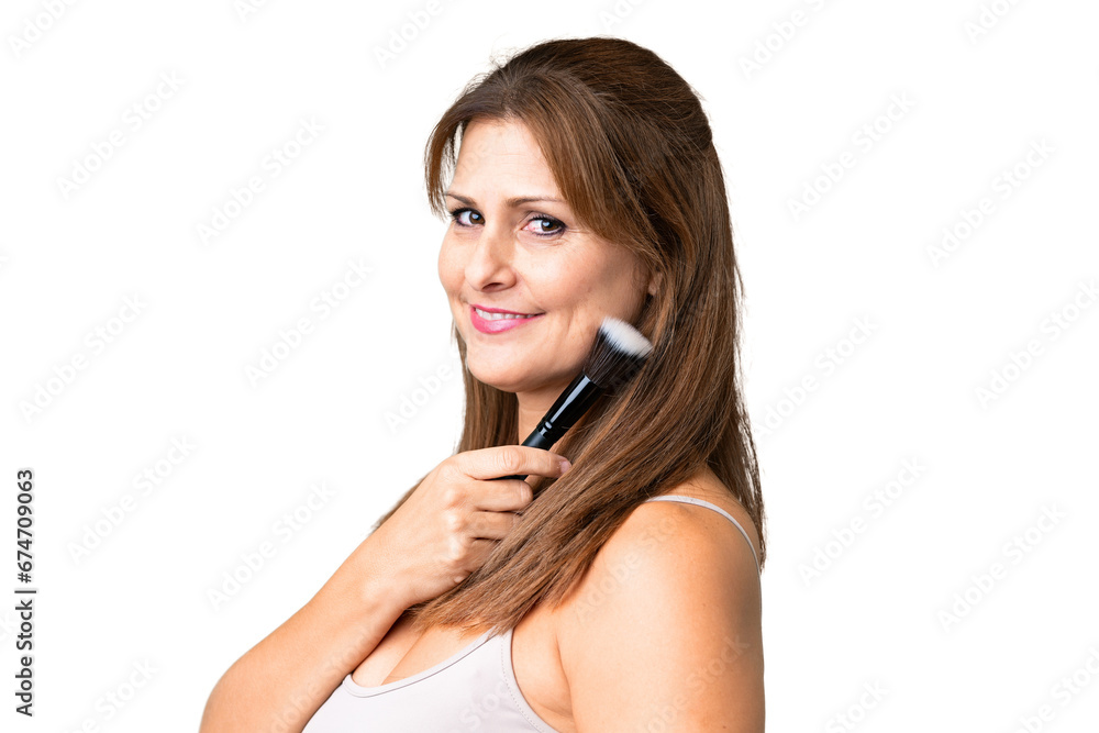 Middle age woman over isolated background holding makeup brush Middle age woman over isolated background holding makeup brush