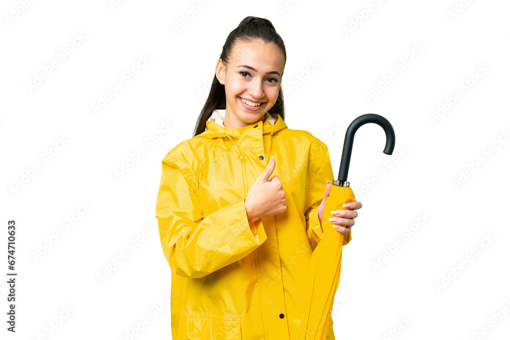 Young Arabian woman with rainproof coat and umbrella over isolated chroma key background giving a thumbs up gesture Young Arabian woman with rainproof coat and umbrella over isolated chroma key background giving a thumbs up gesture