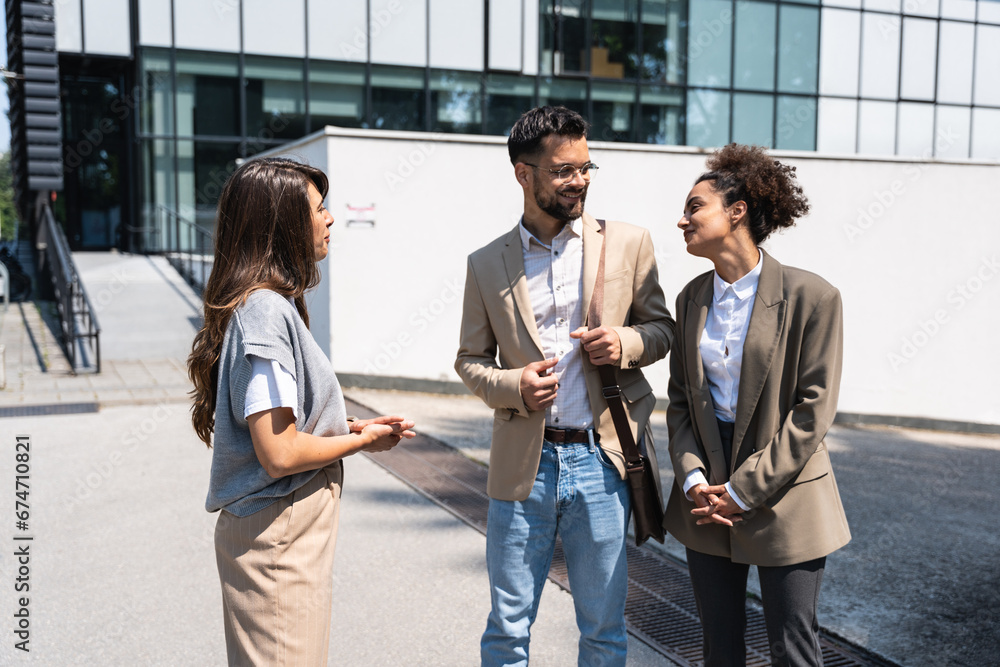 Group of successful young business people, leaders in marketing and motivation, stand in front of office building and consult before a meeting with employees. HR communication in companies concept Group of successful young business people, leaders in marketing and motivation, stand in front of office building and consult before a meeting with employees. HR communication in companies concept