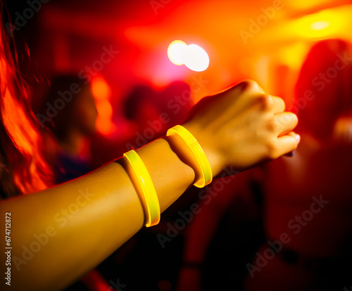 Girl\'s arm wearing a glowing wristband while at a Rave party or clubbing. Concept of nightlife, dancing and drugs and abuse in the nightlife scene. Shallow field of view.