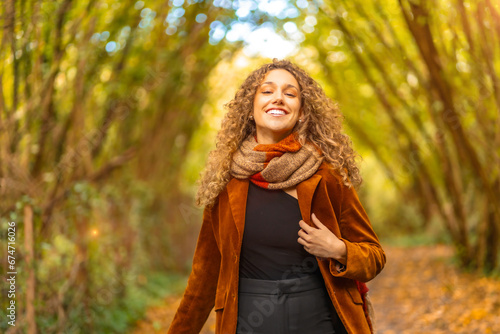 Happy woman in casual warm clothes walking along a park
