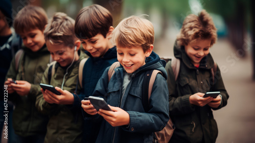 Kids browsing playing online games on mobile phones, small boys with backpacks watching videos on smartphones, standing next to each other