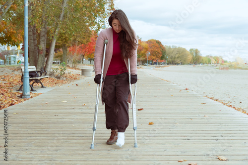 woman with a broken foot walking on a wooden bridge photo