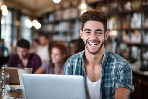 Portrait of smiling young man using laptop in cafe at the coffee shop
