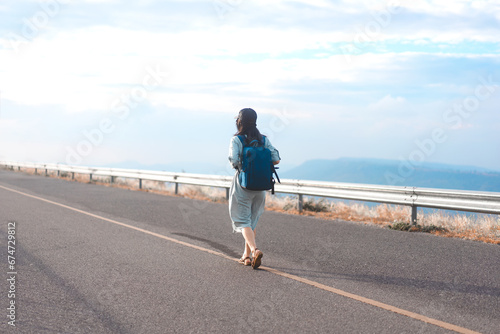 Rear view of young woman traveler with backpack freedom travel minimal background with blue sky © dodotone