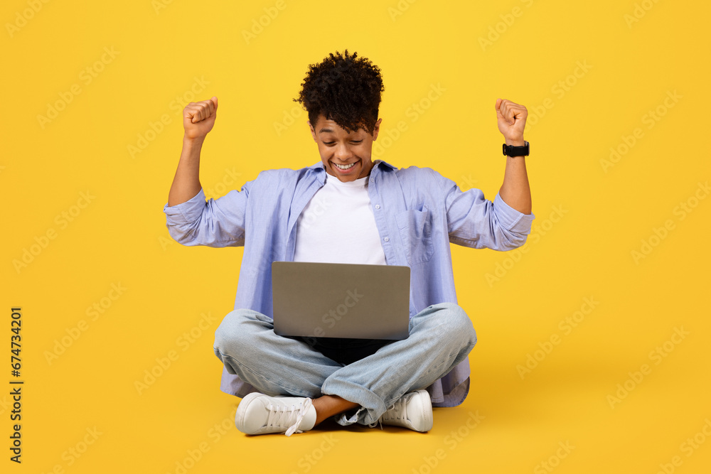 Joyful black male student with laptop celebrating success Joyful black male student with laptop celebrating success