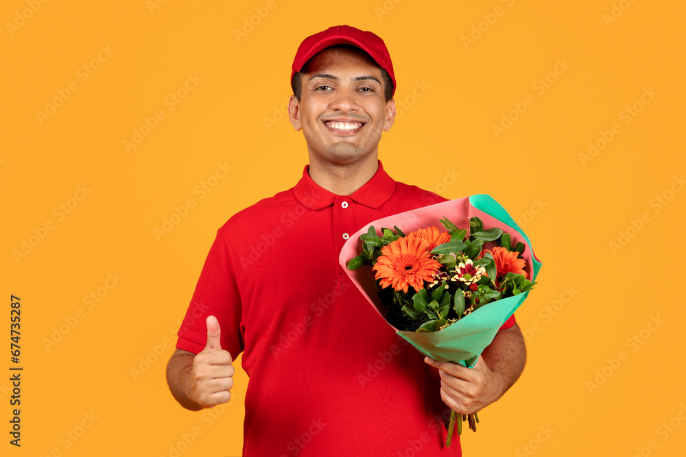 Middle Eastern courier guy holds bouquet gesturing thumbs up, studio Middle Eastern courier guy holds bouquet gesturing thumbs up, studio