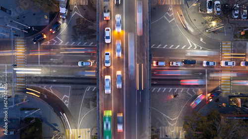 A busy intersection with a lot of cars, buses and trucks. Aerial view from the drone on the night road, the city and pedestrians. Lights and headlights are shining. A traffic jam has formed. Almaty