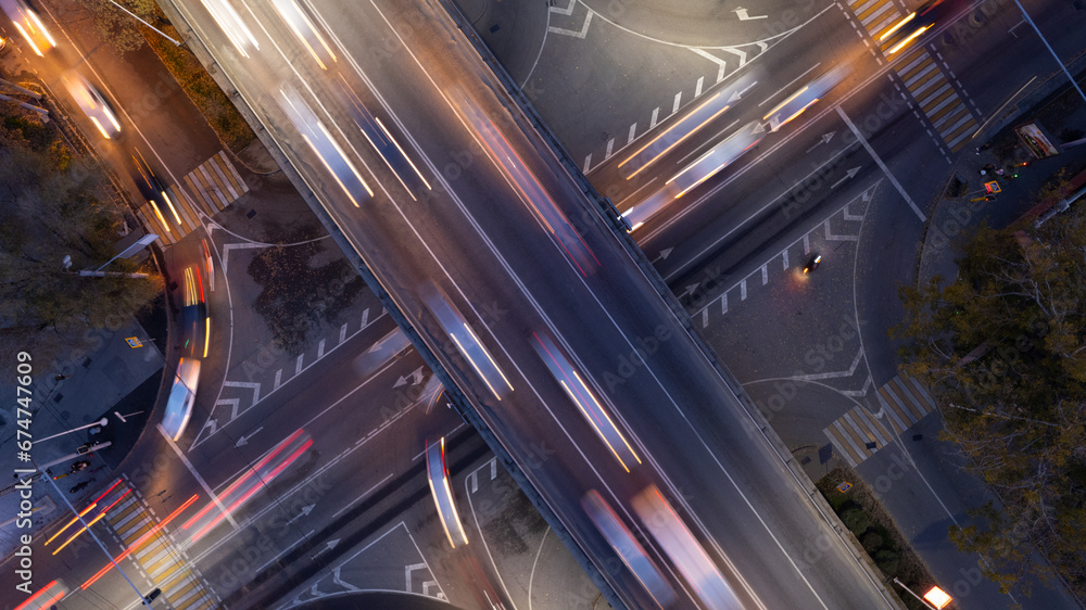 A busy intersection with a lot of cars, buses and trucks. Aerial view from the drone on the night road, the city and pedestrians. Lights and headlights are shining. A traffic jam has formed. Almaty