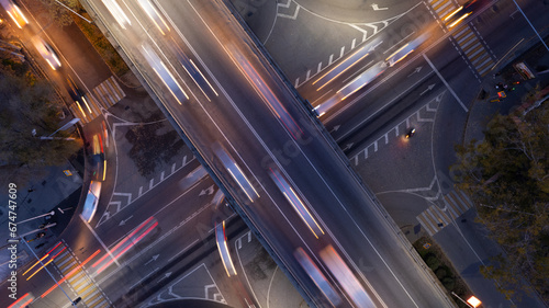 Obraz na płótnie A busy intersection with a lot of cars, buses and trucks. Aerial view from the drone on the night road, the city and pedestrians. Lights and headlights are shining. A traffic jam has formed. Almaty w salonie