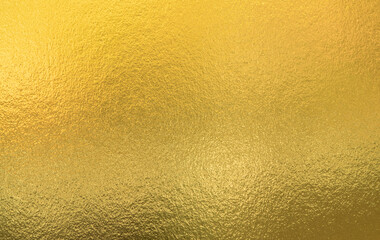 Gold wall texture background. Yellow shiny gold foil paint on wall sheet with gloss light reflection, vibrant golden paper luxury wallpaper