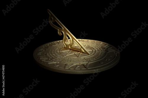 Antique brass sundial with time and calendar engraved on the surface. Isolated on black background photo