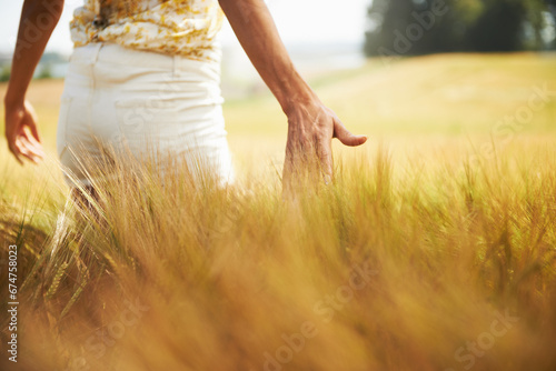 Closeup, walking or back of woman in a field for freedom in the countryside in spring to relax on break. Hands, wellness or person in garden or farm for fresh air on holiday vacation or nature travel