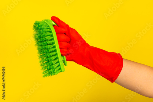 Brush for cleaning in hand. Women s hand cleaning on a colored background. Cleaning or housekeeping concepts.