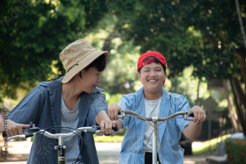 Asian boy is spending his free times by riding bike with his friend in his school park at the weekend, soft and selective focus. #674793642