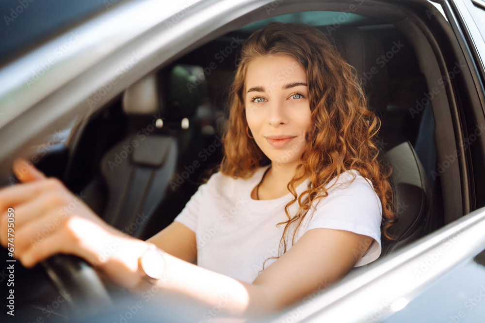 Portrait of a beautiful young woman driving a car. Happy woman traveling by car in casual clothes. Car travel concept. Lifestyle.
