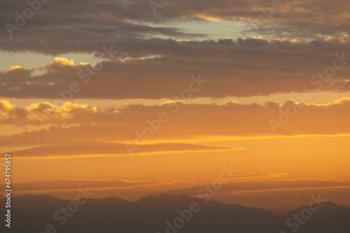 Beautiful bright summer sunset sky with clouds and mountains. Nature sky background.