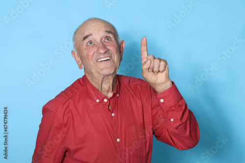 smiling senior man isolated on background pointing up © carballo