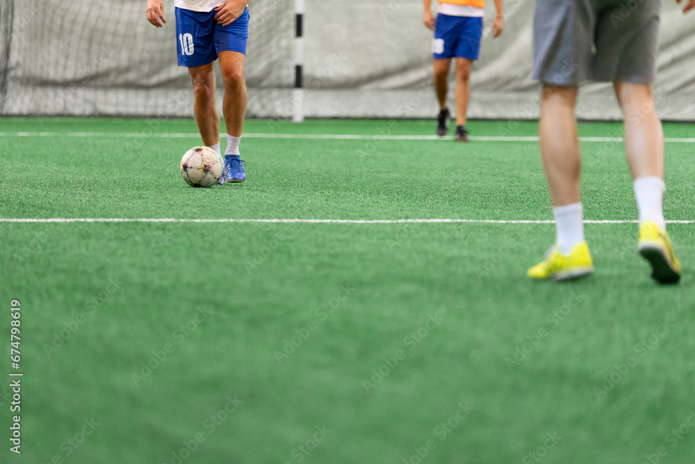 Mini soccer football players playing game in indoor stadium on artificial turf.